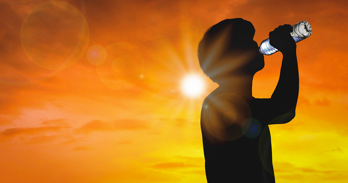Silhouette man is drinking water bottle on hot weather background with summer season.