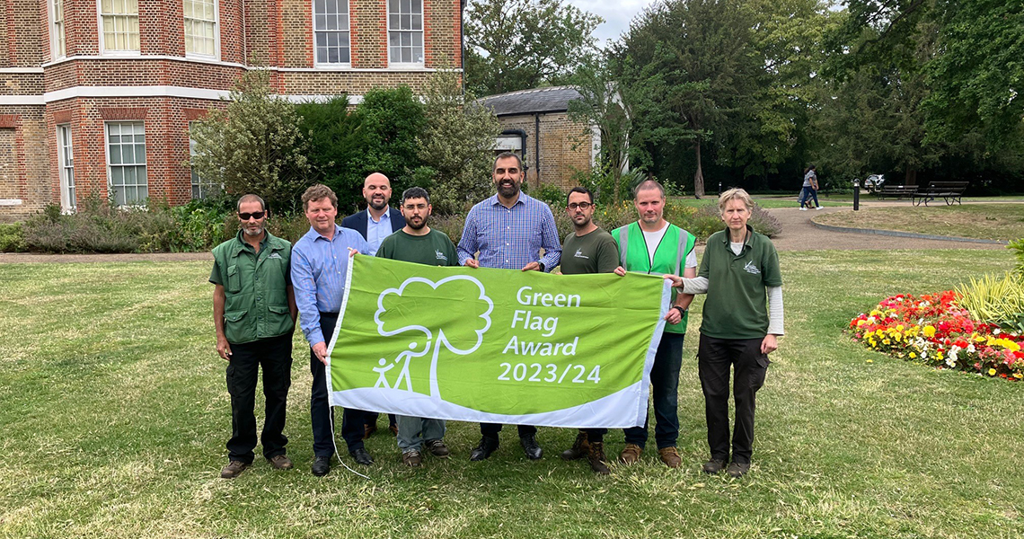 Deputy Leader and parks staff standing with flag in Valentines Park
