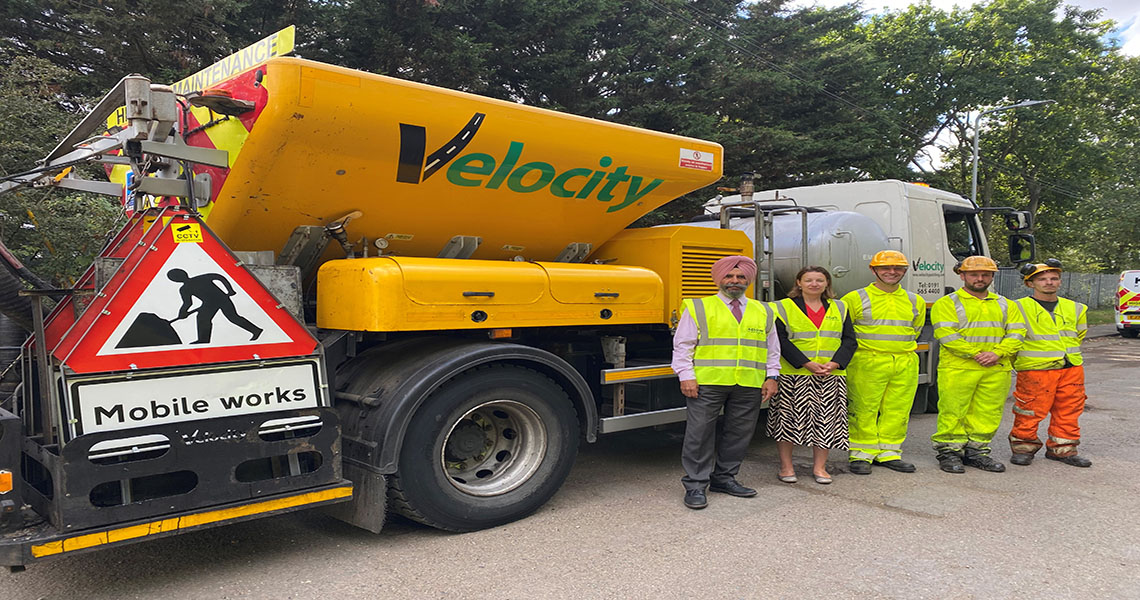 pothole repair machine with people next to it