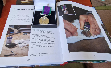 War medal placed on top of a book featuring Gordon's visit to BBC's The Repair Shop