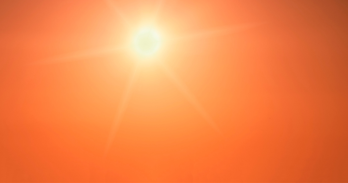 Sunlight illuminates a vibrant orange sky, creating a warm and radiant atmosphere.