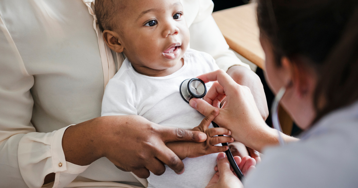 A doctor examines a baby during a routine check-up in a clinical setting.