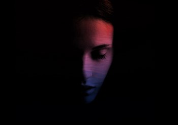 woman looking down with most of her face covered in darkness