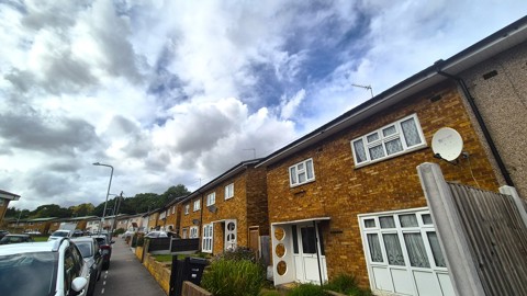 Row of semi-detached houses on residential street with parked cars