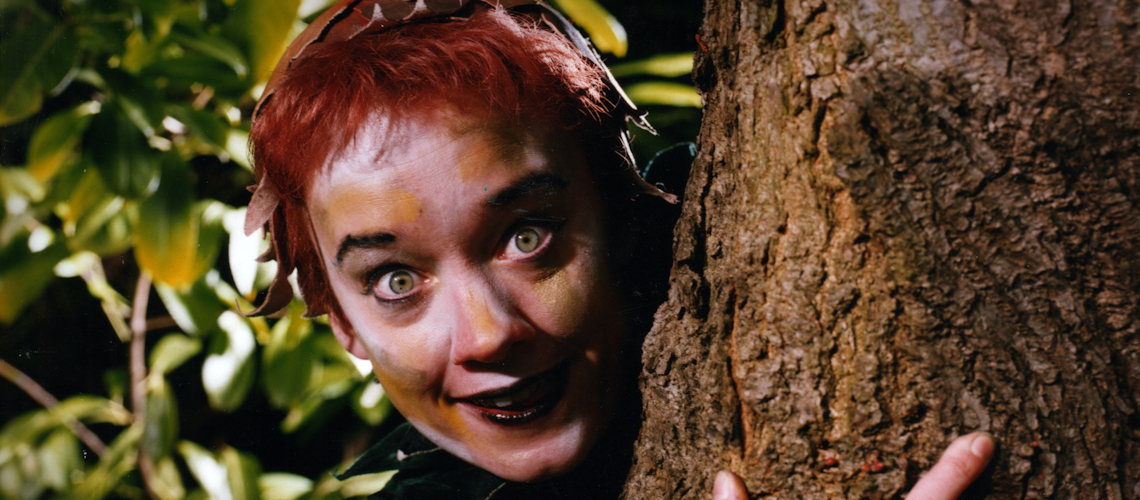 woman peeking out from behind a tree