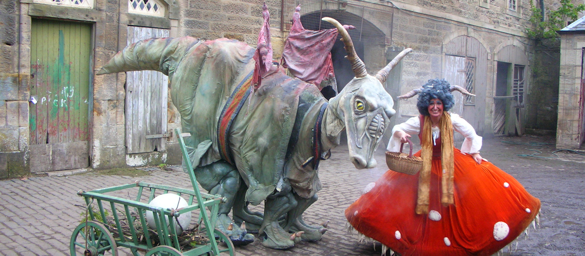 woman dressed as goblin queen standing next to a dragon