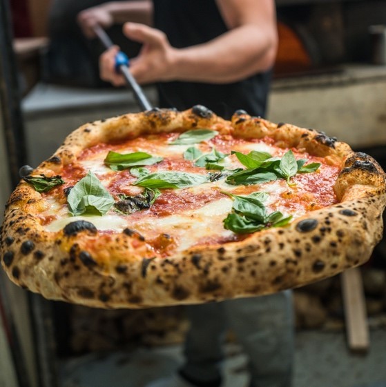 Cheese pizza coming out of wood fire oven
