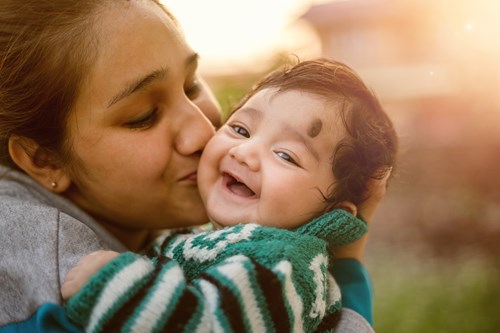 Female foster carer kissing the cheek of a baby who is in their care