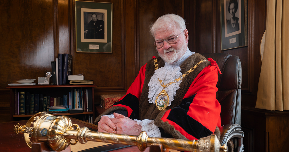 Roy Emmett sits behind his desk which has the ceremonial mace on it