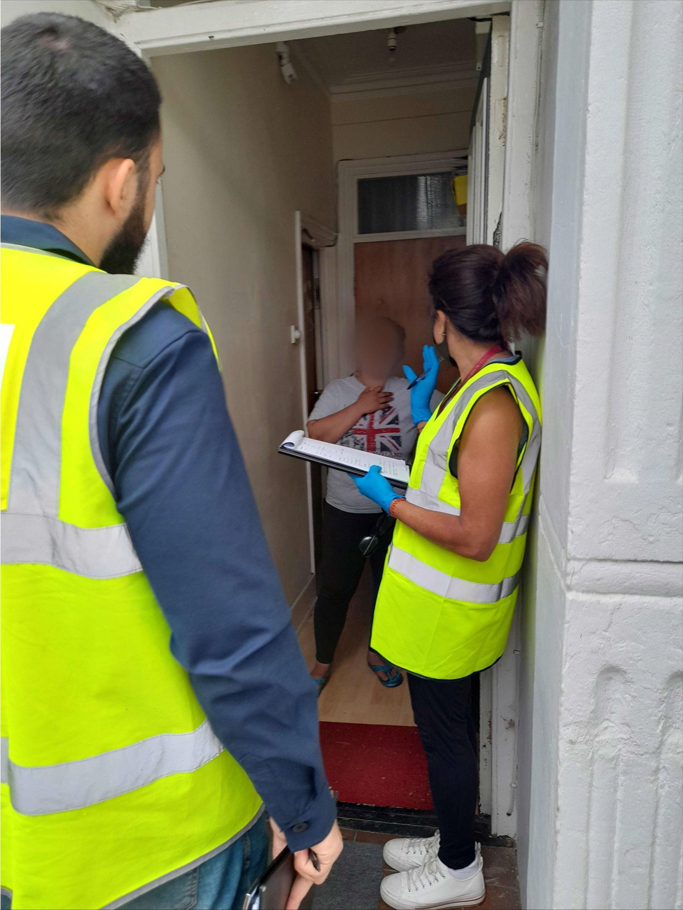two men in high-vis jackets at door of resident taking survey results