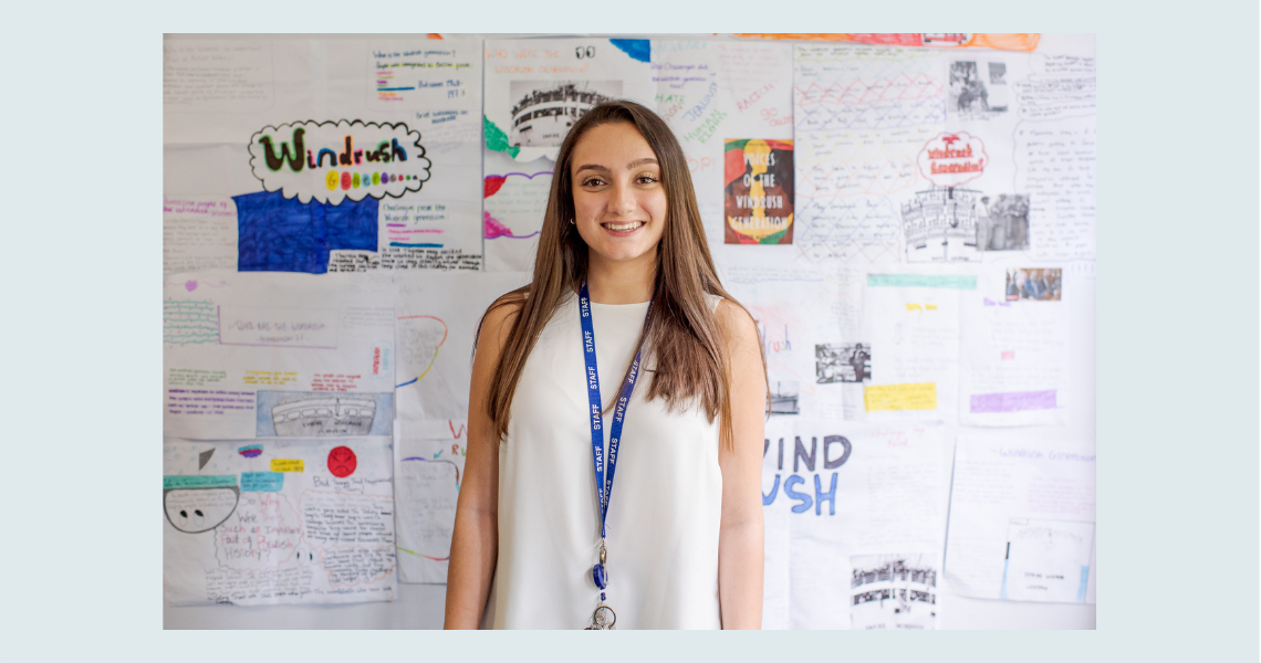 Awarding teacher Amara stands against backdrop of student work