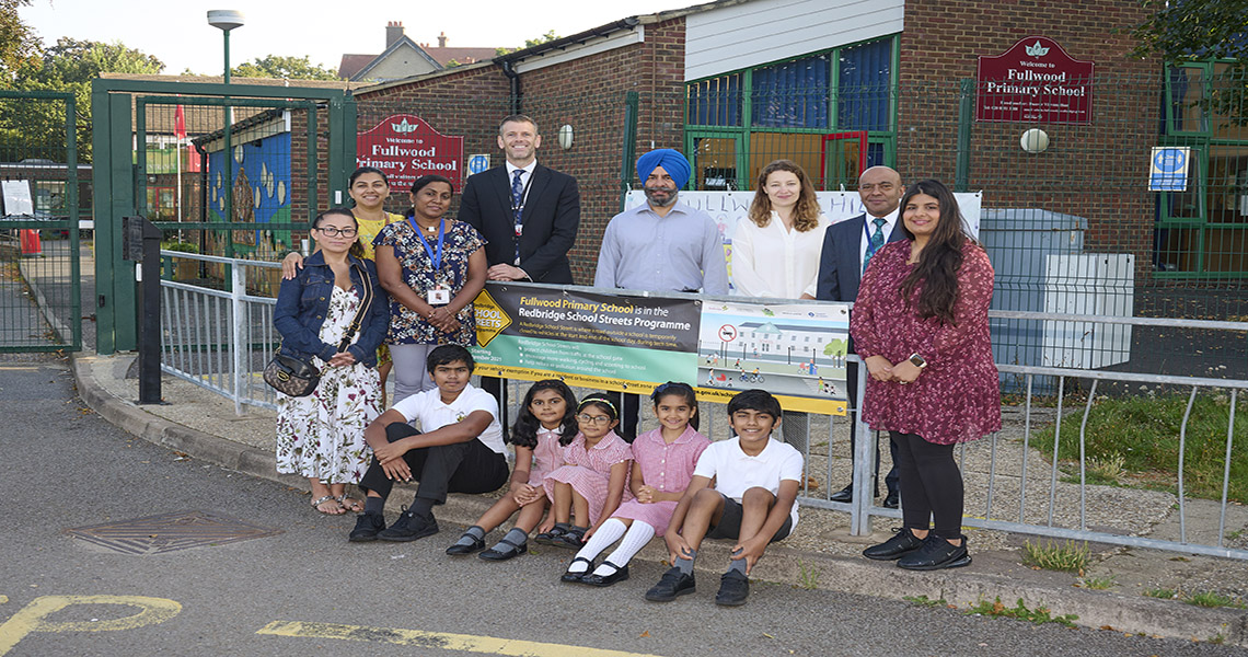 group image of members of school staff, council staff and children from school, all posed by school street sign by school