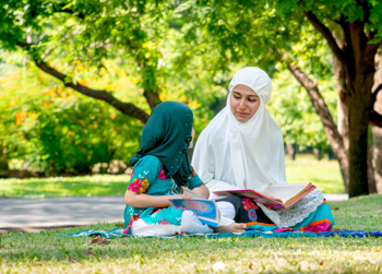 Female adult and young female child reading in a park