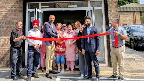 Councillors and community groups cutting a red ribbon to open Janice Mews