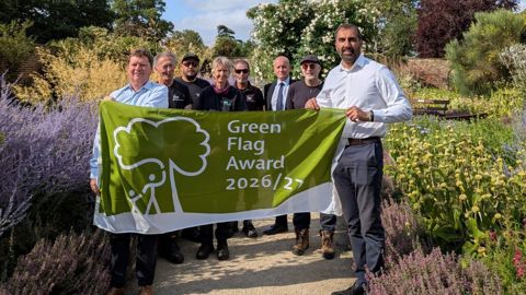 Leader of the council and parks colleagues with a green flag award flag in Valentines Park