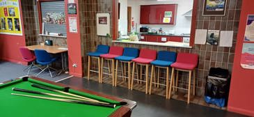 Inside the main room at Hainault Youth Centre looking through the hatch into the kitchen. Red and blue high chairs in front of the hatch