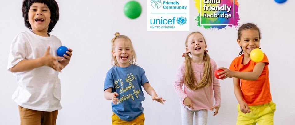 Four young children having fun, throwing coloured balls, with the UNICEF UK and Child Friendly Redbridge logos in the background