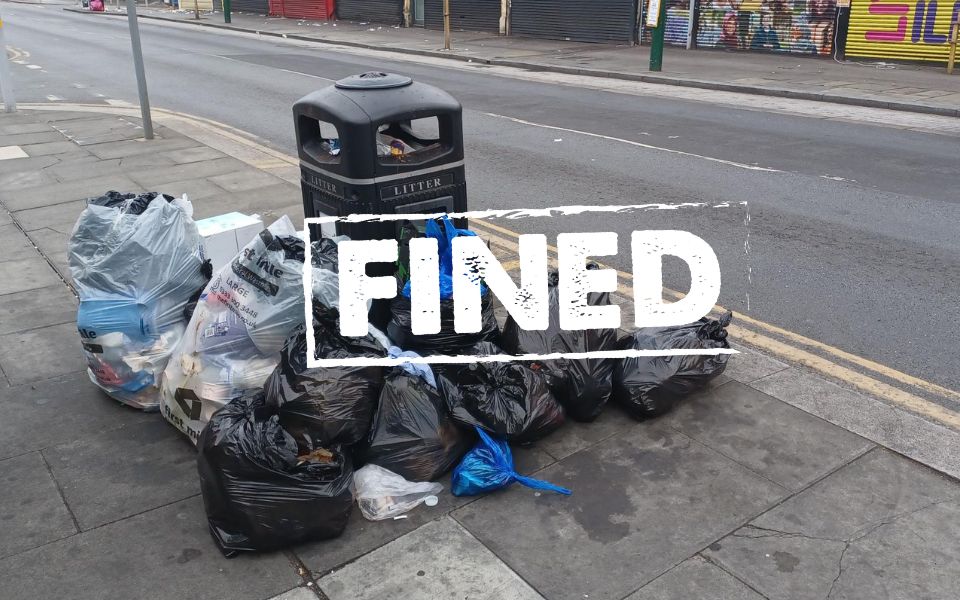 image of rubbish by bins with sign across it saying fined.