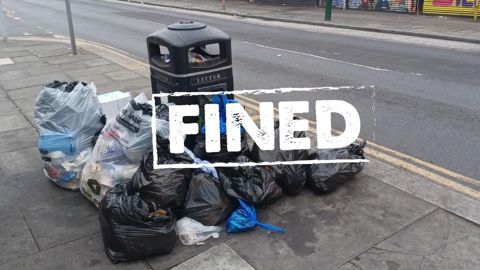 image of rubbish by bins with sign across it saying fined.