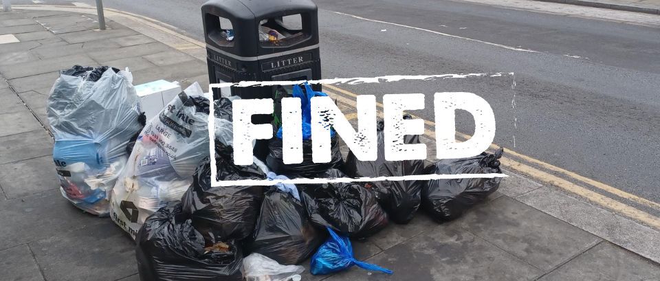 image of rubbish by bins with sign across it saying fined.