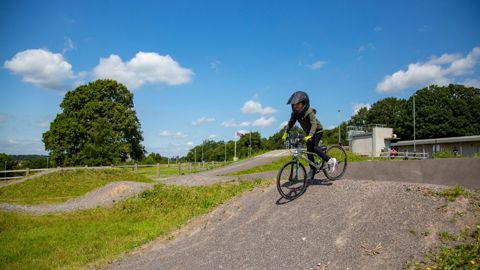 A child cycling on the BMX track at Redbridge cycling centre, wearing a helmet