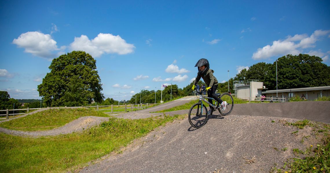 A child cycling on the BMX track at Redbridge cycling centre, wearing a helmet