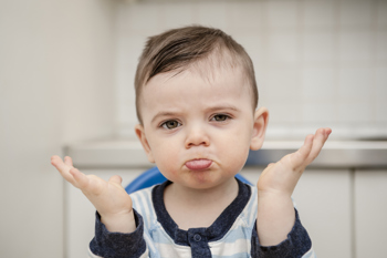 Male toddler raising his hands in a quizzical manner