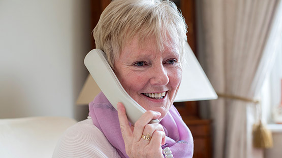 Lady holding telephone handset to ear and smiling image