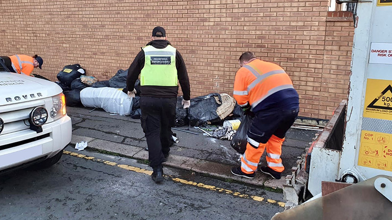 Member of the enforcement team with a bin collection officer picking up fly tip rubbish image