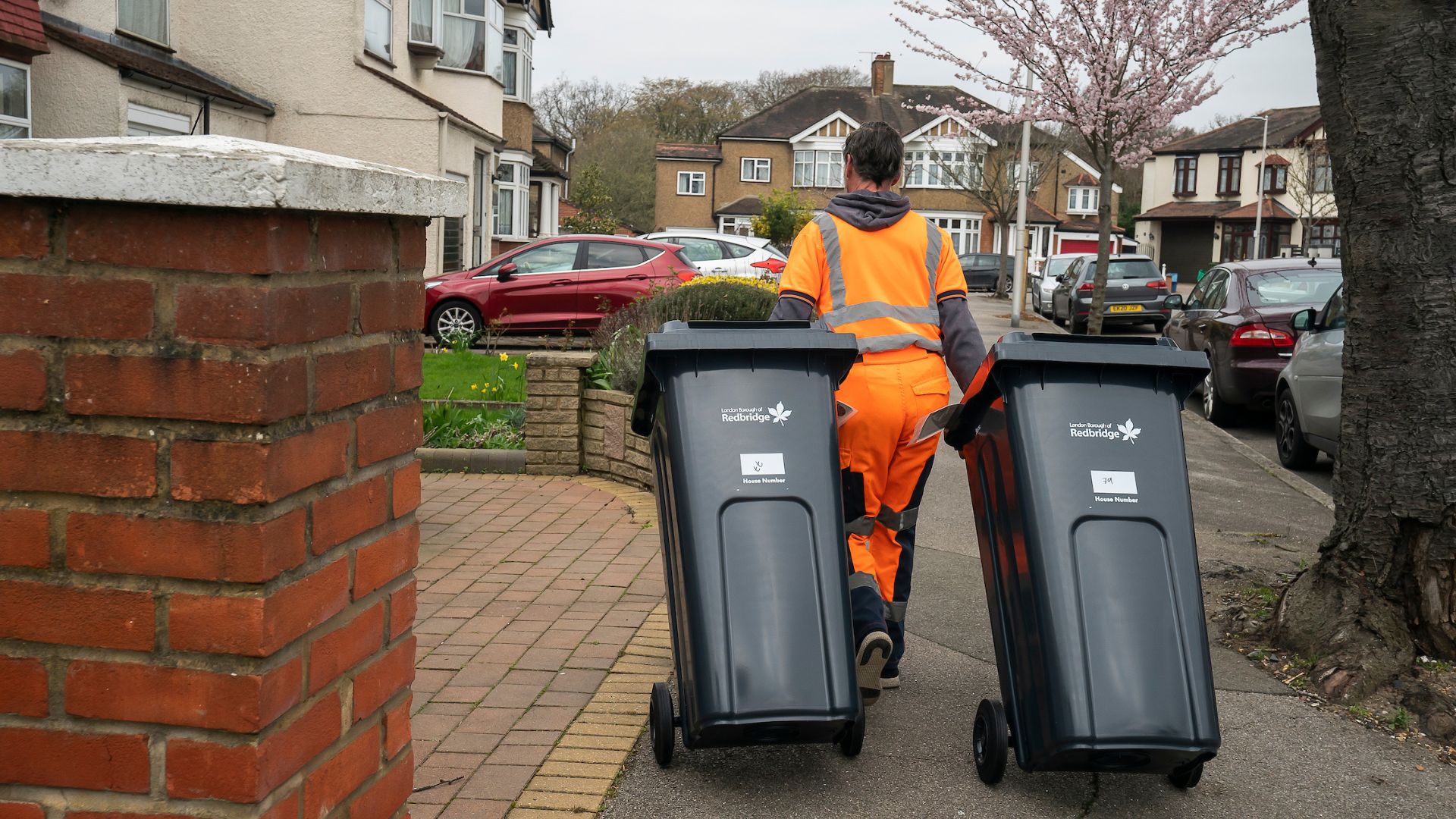 Refuse worker collecting two refuse bins image