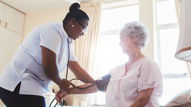 Nurse taking the blood pressure of an elderly lady image