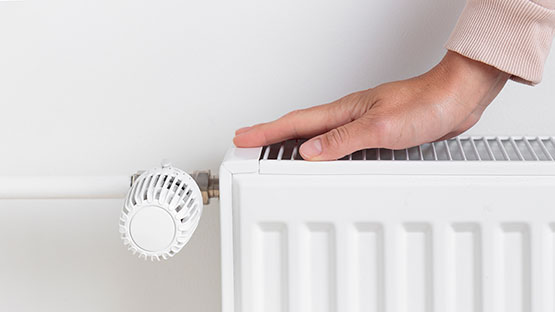 Hand touching the top of a double heating radiator image