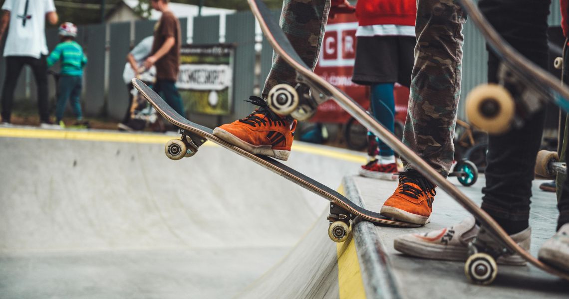 Legs and feet on skateboards at the edge of a skate park slope